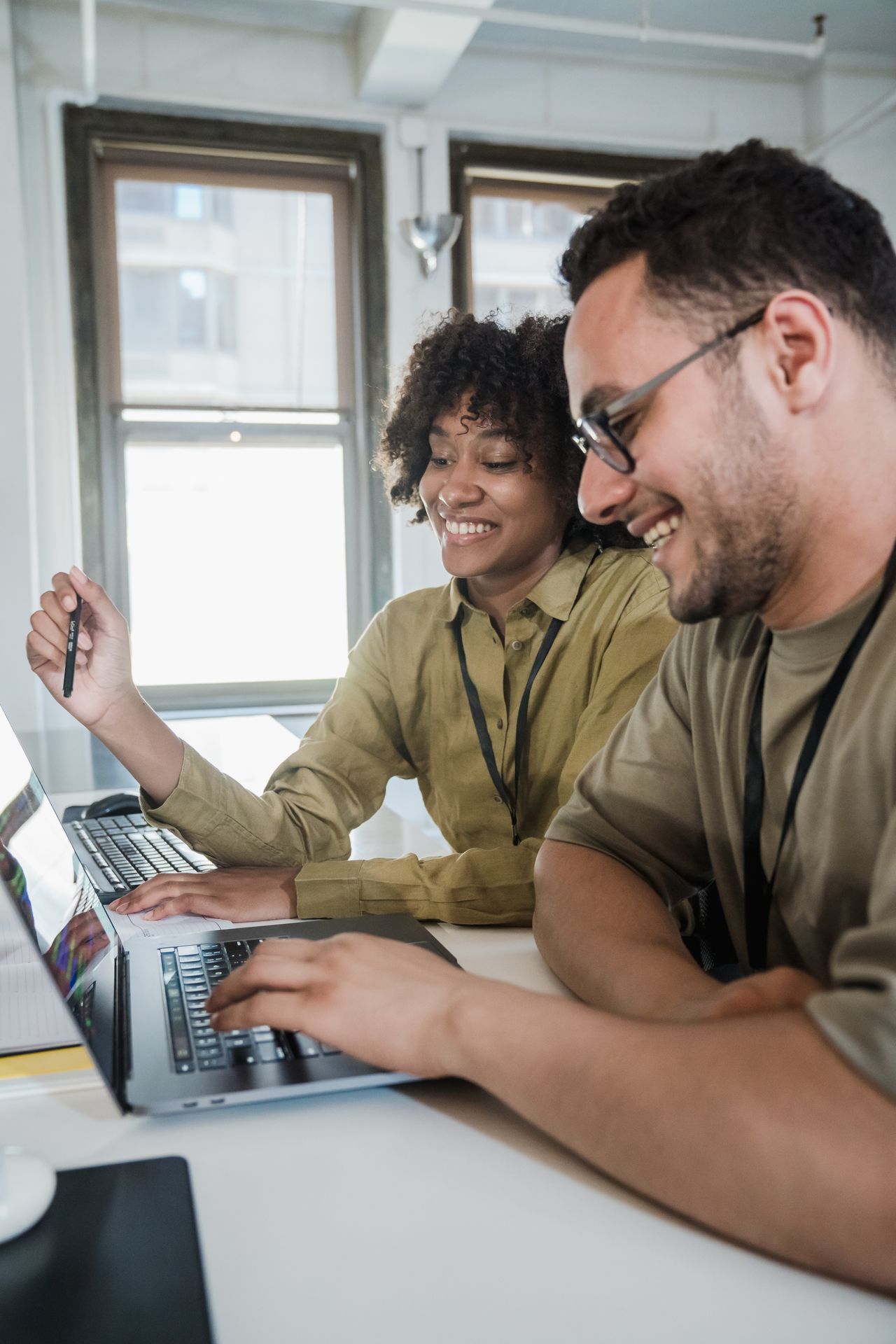 Two colleagues smiling and working together at a laptop